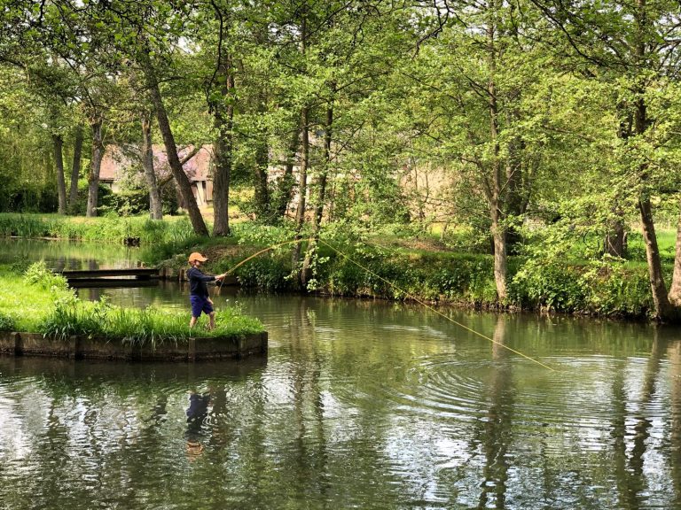 Pêcheur à la mouche sur la rive opposée de l'étang