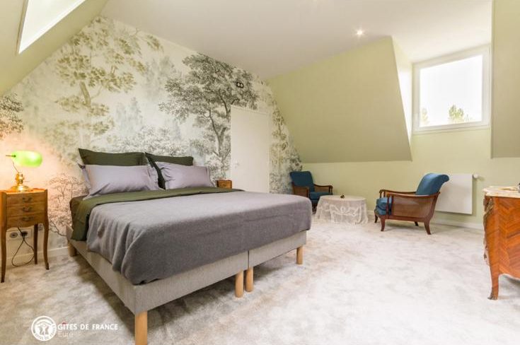 Chambre avec lit double et papier peint aux motifs d'arbres
