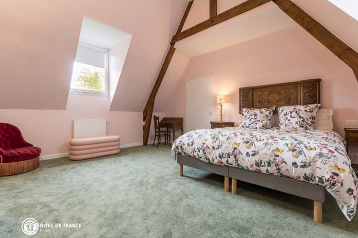Chambre avec tête de lit en bois, couette fleurie et fenêtre de toit