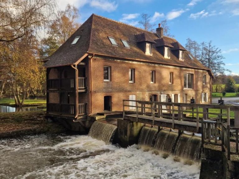 Le moulin en brique et son déversoir en automne, vu depuis la passerelle