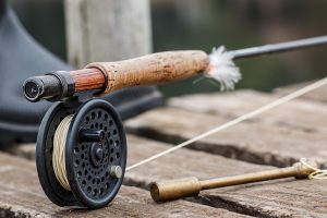 Gros plan sur un moulinet et une canne à mouche posés sur du bois