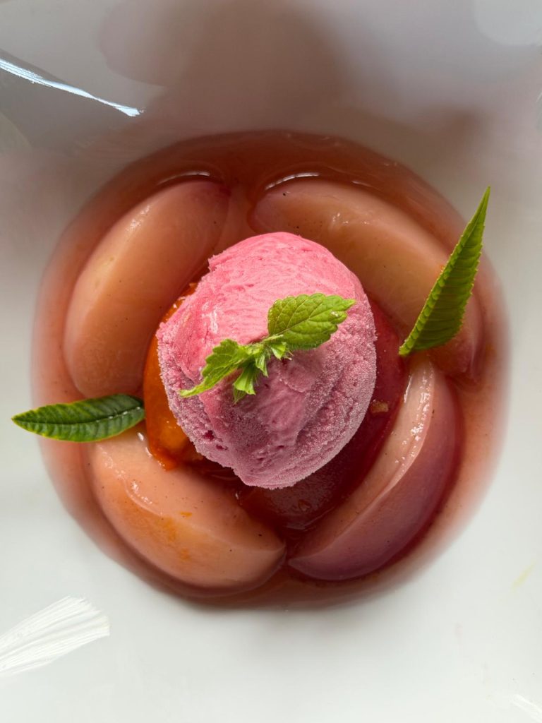 Pêches pochées et sorbet aux fruits rouges, décorés de menthe et de verveine