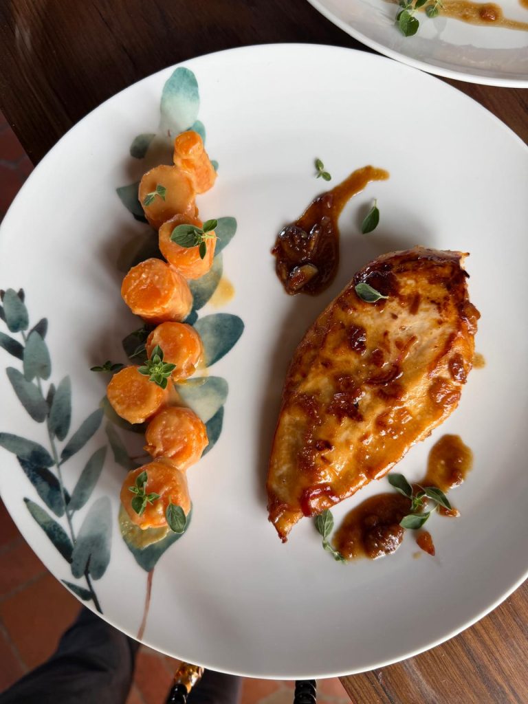 Suprême de volaille laqué, carottes glacées et jus corsé, servi à la table d'hôtes