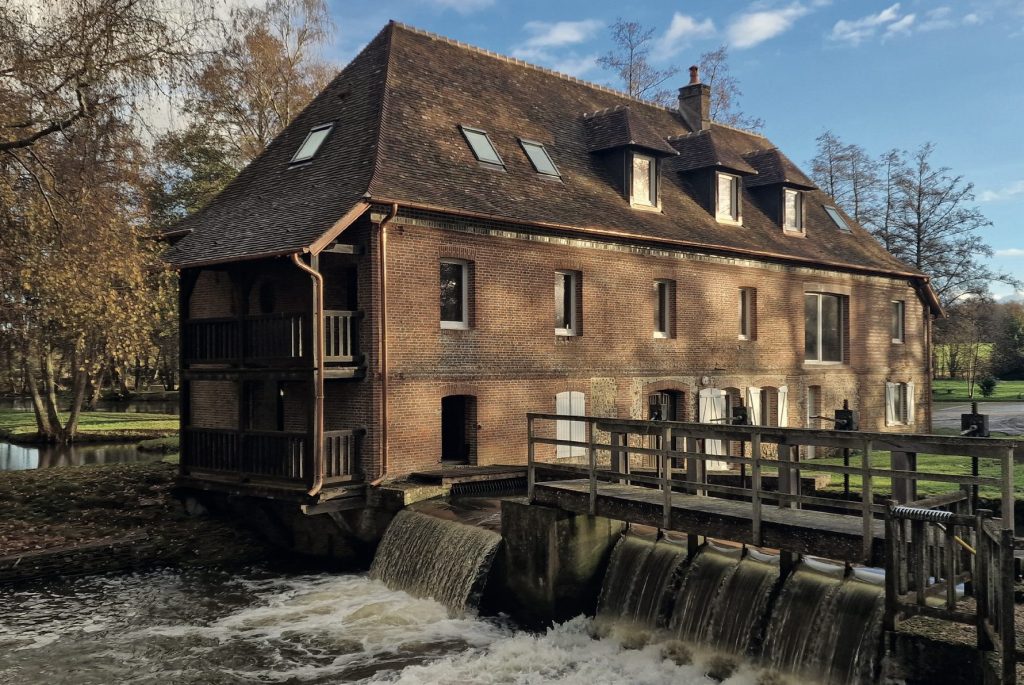 Le moulin de Chaise-Dieu du Theil en automne, l’eau du déversoir tombant sous la passerelle de bois