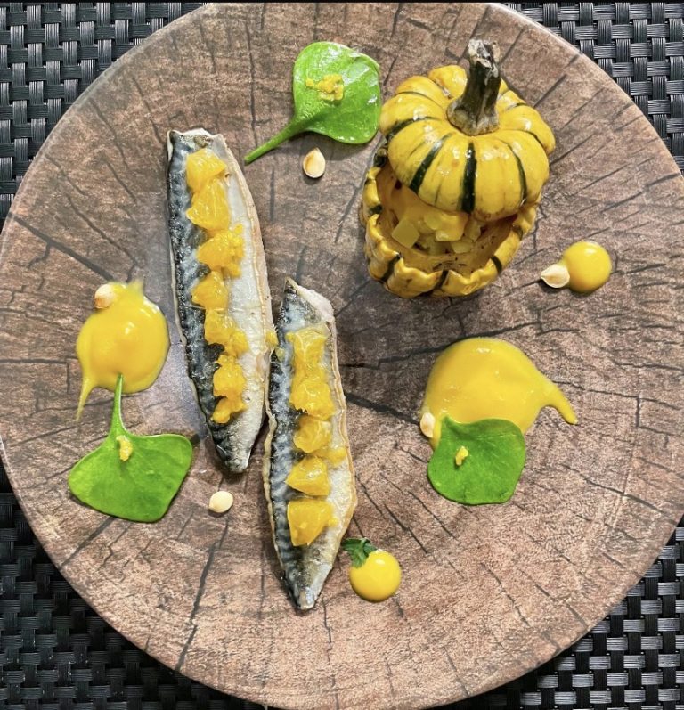 Filets de maquereau aux dés d’agrumes, courge sweet dumpling farcie et purée de courge, dressés sur une assiette en bois