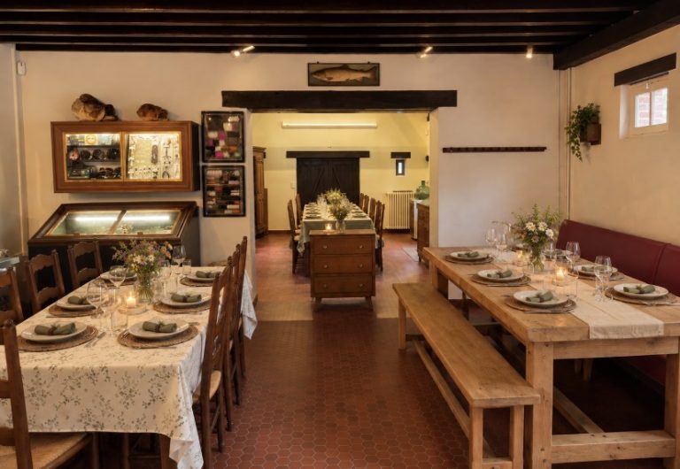 La salle de restaurant du Moulin de Chaise-Dieu du Theil, tables dressées aux bougies et aux fleurs, vitrines de mouches de pêche et truite naturalisée au mur