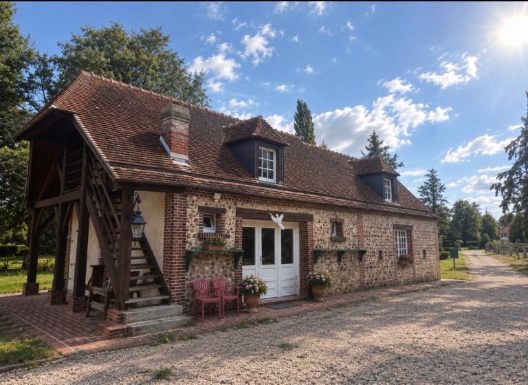 Bâtiment en brique et silex du Moulin sous le soleil, avec son escalier extérieur couvert et ses lucarnes à volets sombres